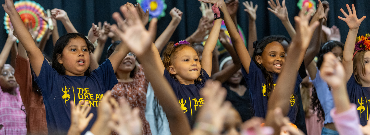 Surrounding by other students, three students lifts their hands in the air during the Hispanic Heritage Program.