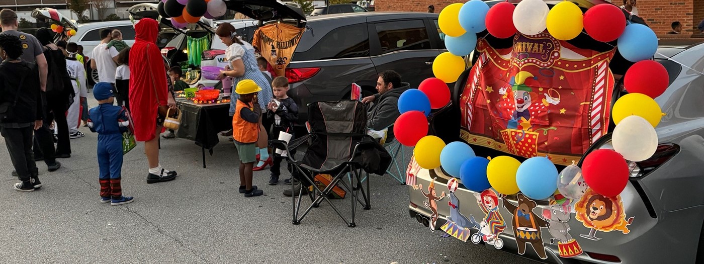 Students dressed up costumes playing games in the parking lot during the PTA Trunk or Treat event.