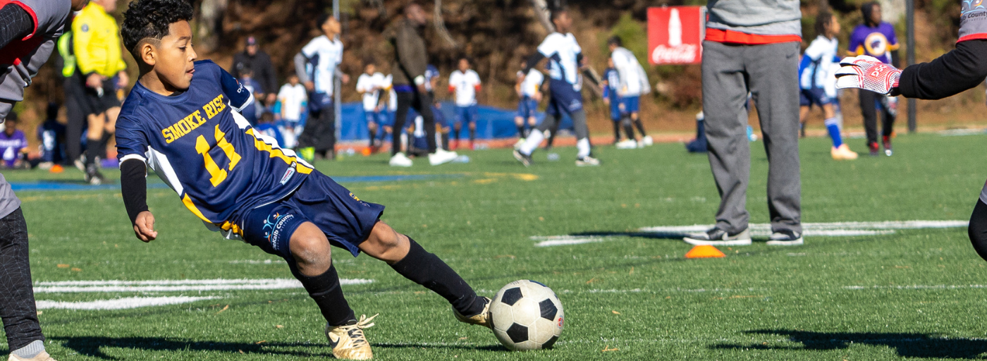 Student kicking a soccer ball on a field.