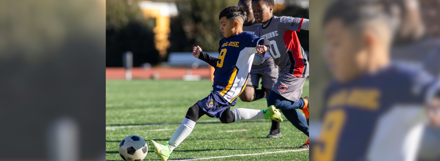 Student kicking a soccer ball on a field.