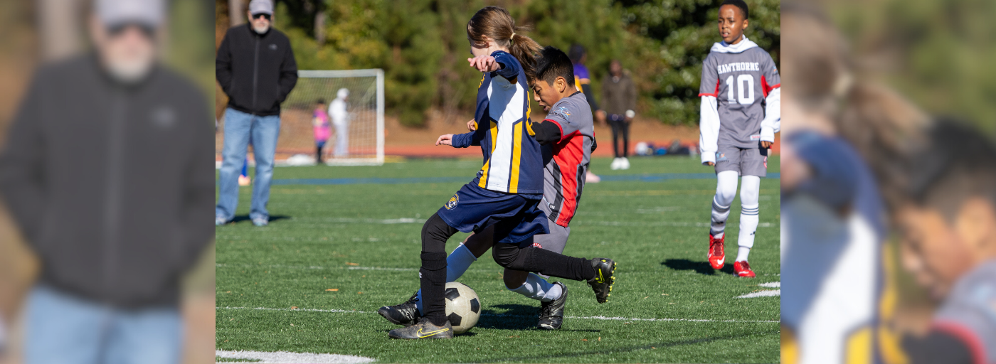 Student kicking a soccer ball on a field.