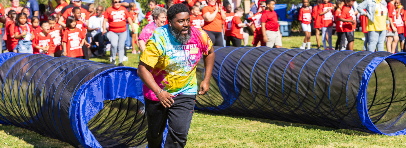 Field Day 2024 - A parent running in an obstacle course