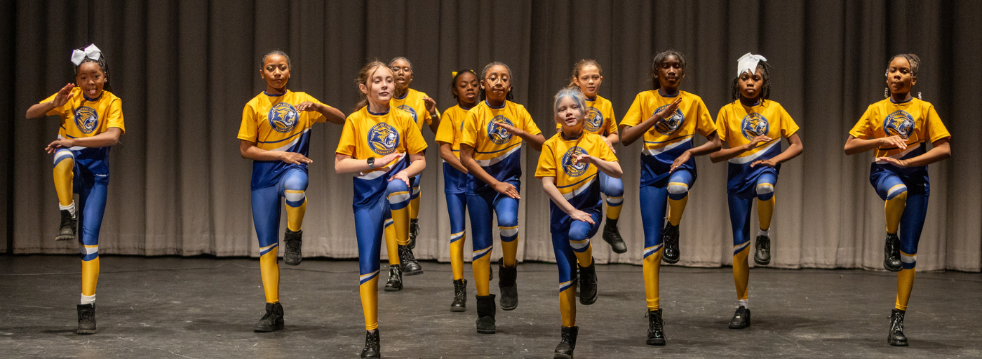 A group of girls in dance uniform on a stage dancing.